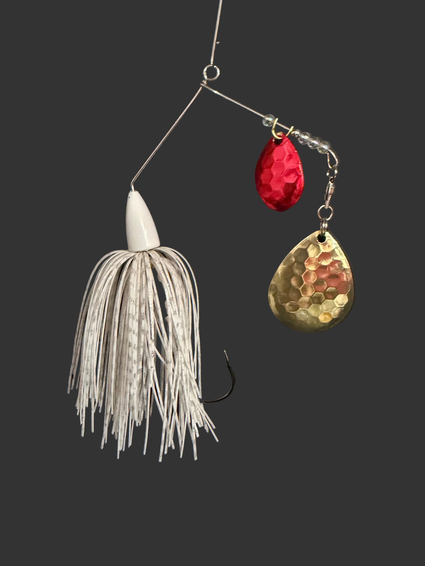 3/8oz Bass Spinnerbait with dual red and gold hex Colorado blades and a white skirt on a dark grey background