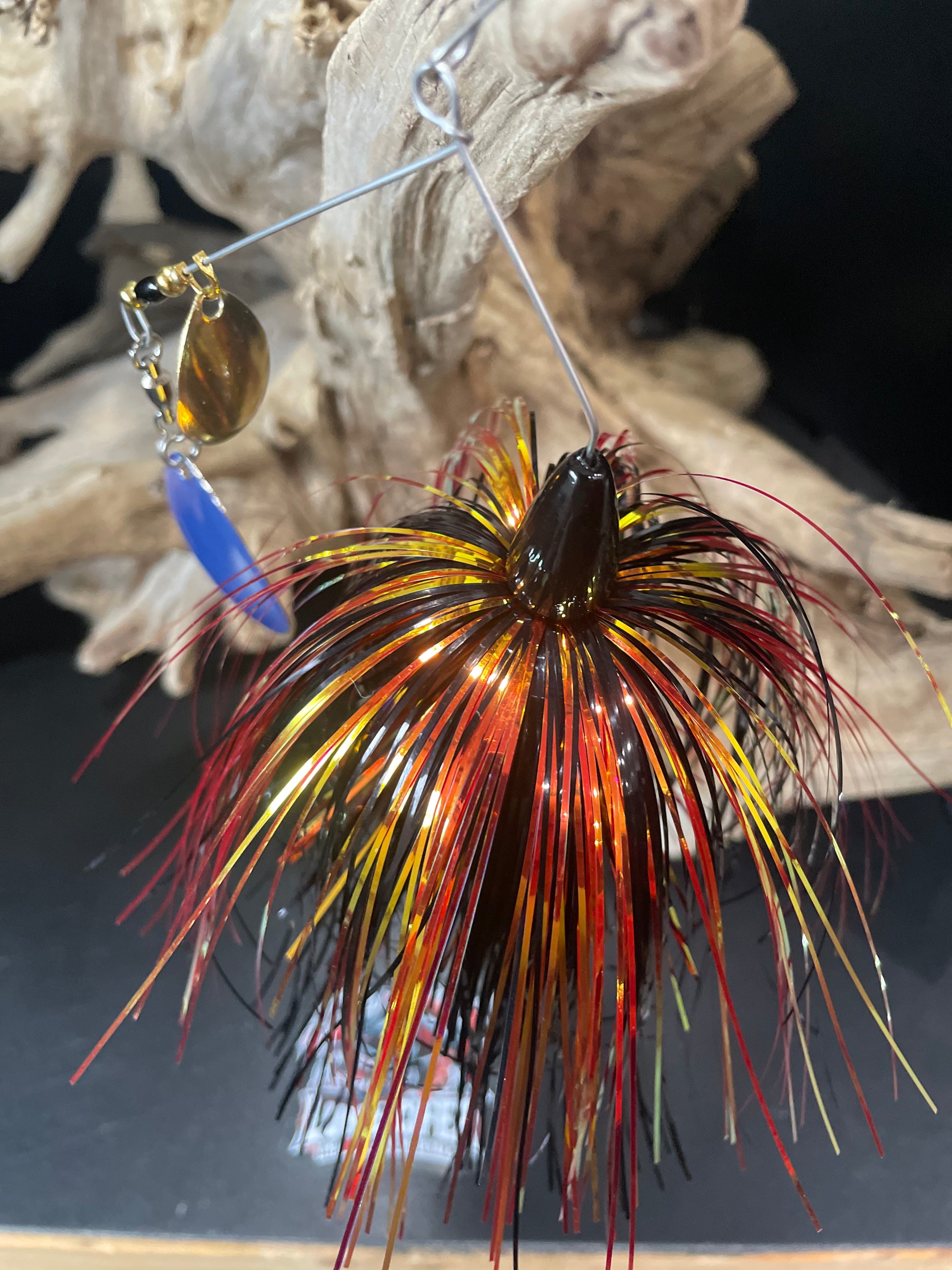 Introducing the Krakatoa, a bass spinnerbait that combines black, gold, and red colours to attract fish and a #7 Colorado Blade with UV glow for added visibility. Available in 1/2 and 3/4 oz options with a #5/0 hook. Catch more bass with this ultimate fishing lure. Picture from above/angle