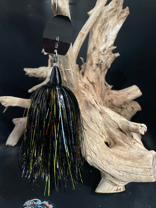 Fishing lure with black and yellow pattern hanging on a piece of driftwood.