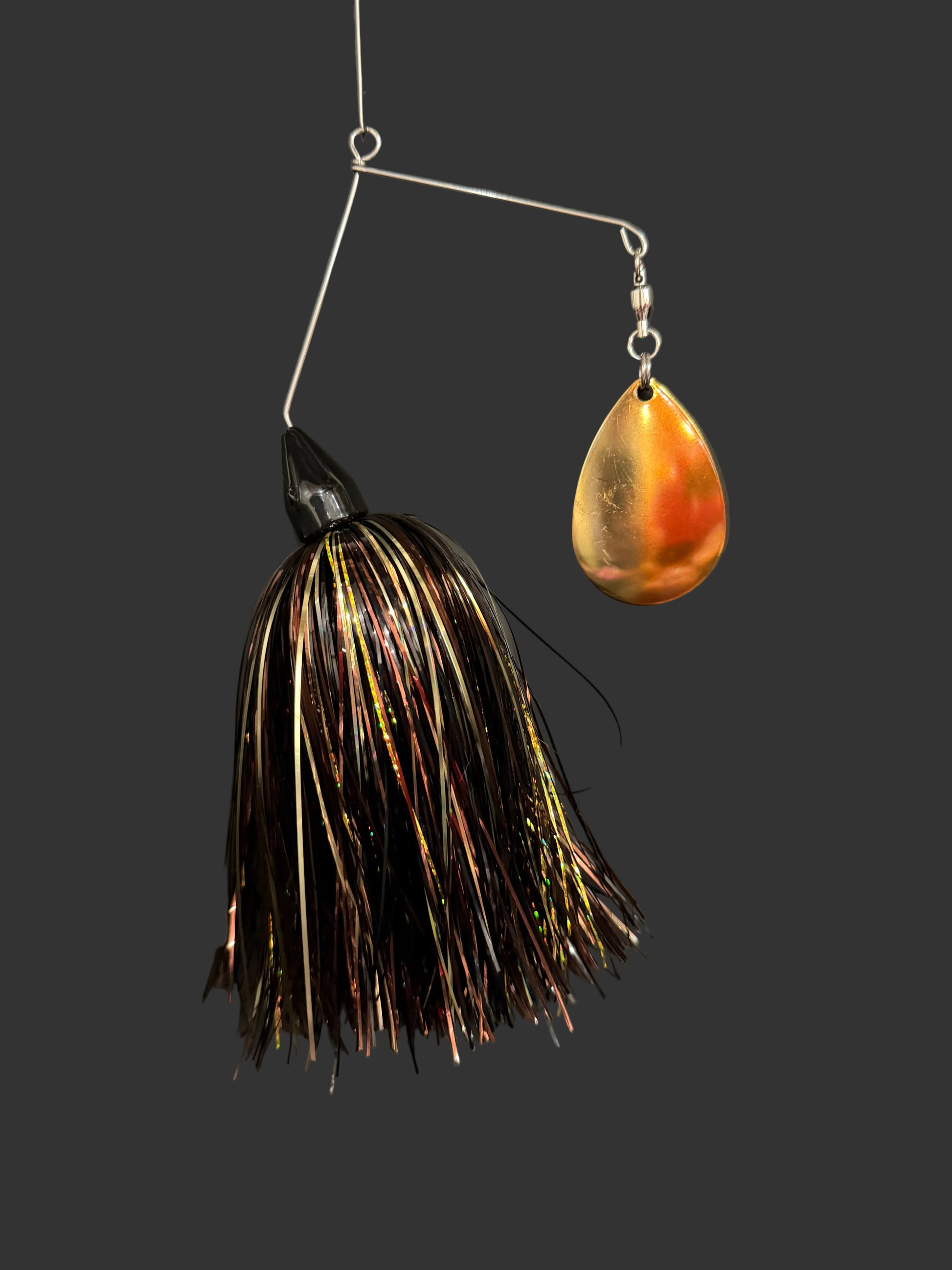 Fishing lure with gold blade and black and gold skirt on a dark background