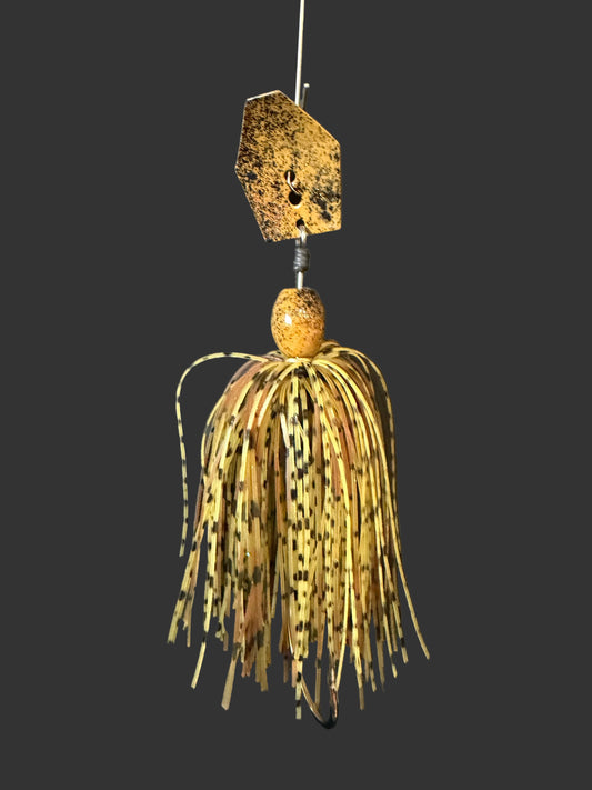 Fishing lure hanging from a branch with a dark background. Natural Brown 3/8oz Chatterbait with black speckles, wired skirt, and a heavy duty #4/0 hook. Ideal for mimicking crawfish/crayfish and targeting big bass.