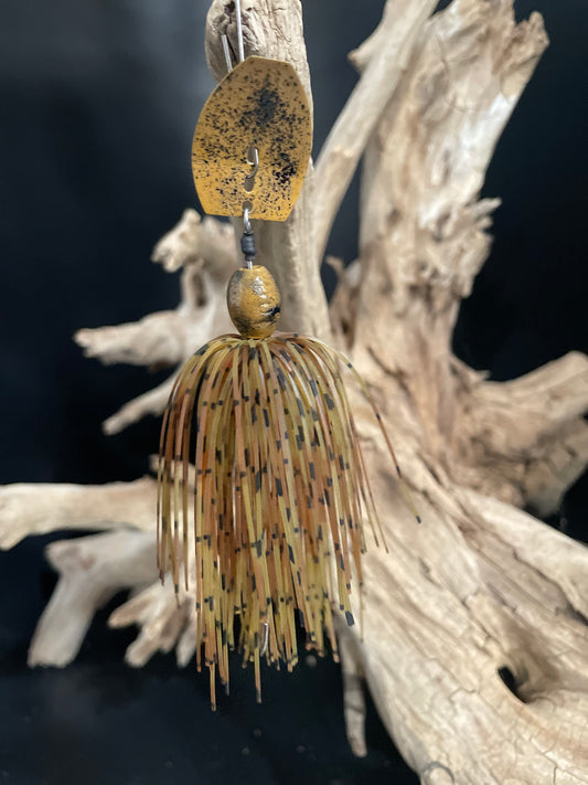 Fishing lure hanging from a branch with a dark background. Natural Brown 3/8oz Chatterbait with black speckles, wired skirt, and a heavy duty #4/0 hook. Ideal for mimicking crawfish/crayfish and targeting big bass.