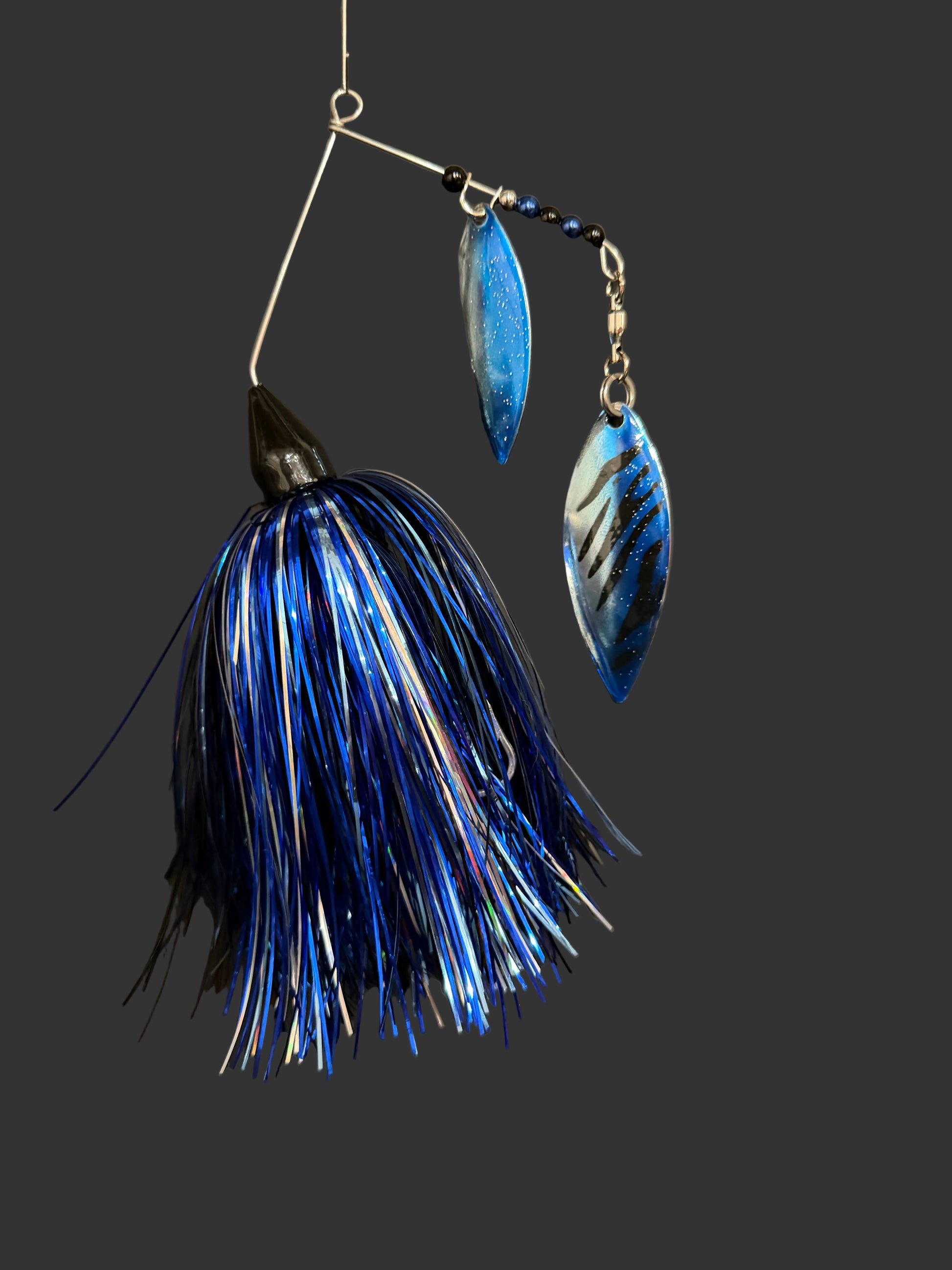 Blue and silver fishing lure on a dark surface