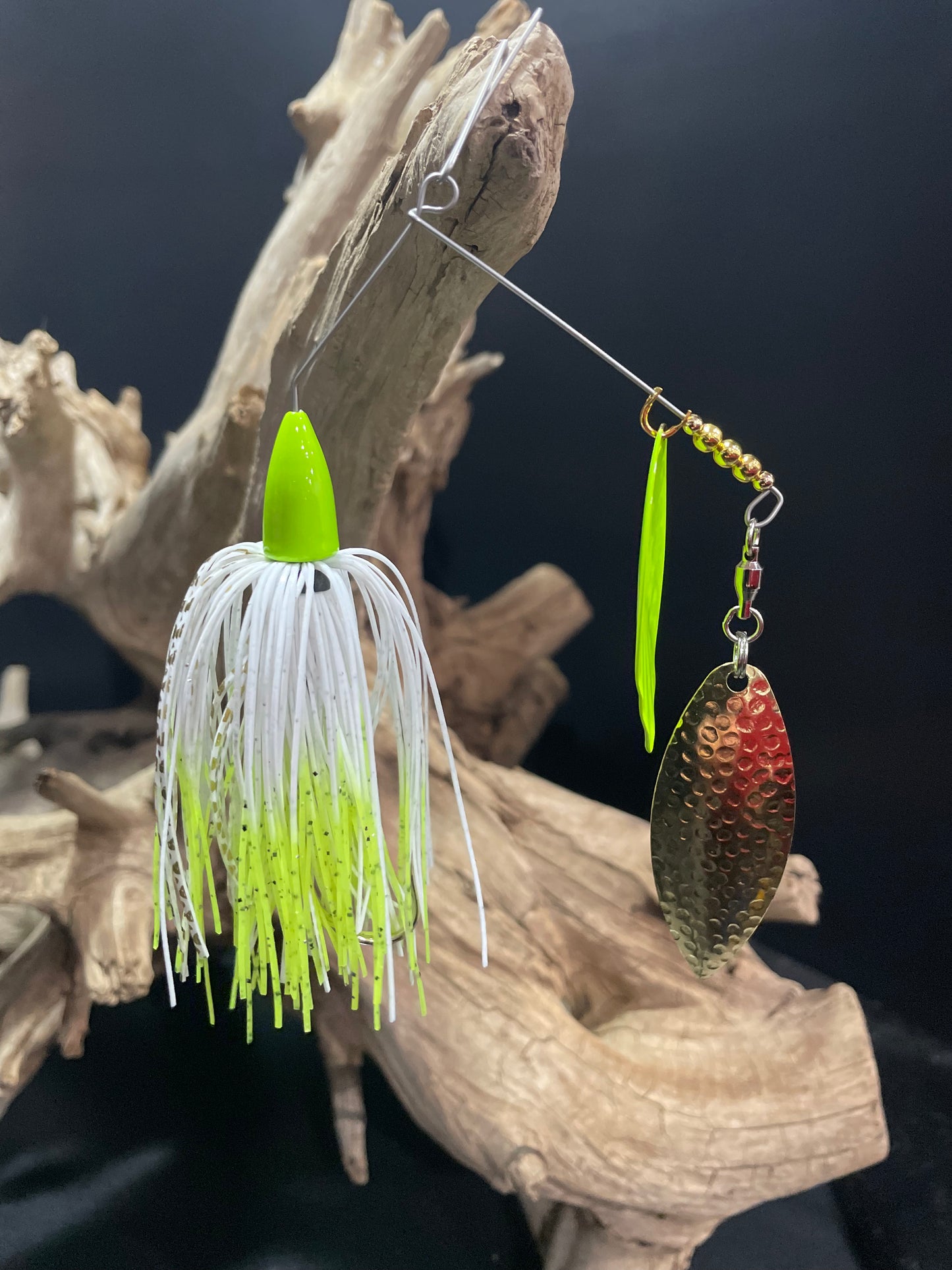 A bass spinnerbait fishing lure, featuring a #5 willow blade paired with a #4.5 and #4/0 hook. Its white and chartreuse design is sure to attract the most elusive fish. Lightweight and equipped with multiple blades, this 3/8 oz lure will improve your fishing game by leaps and bounds.