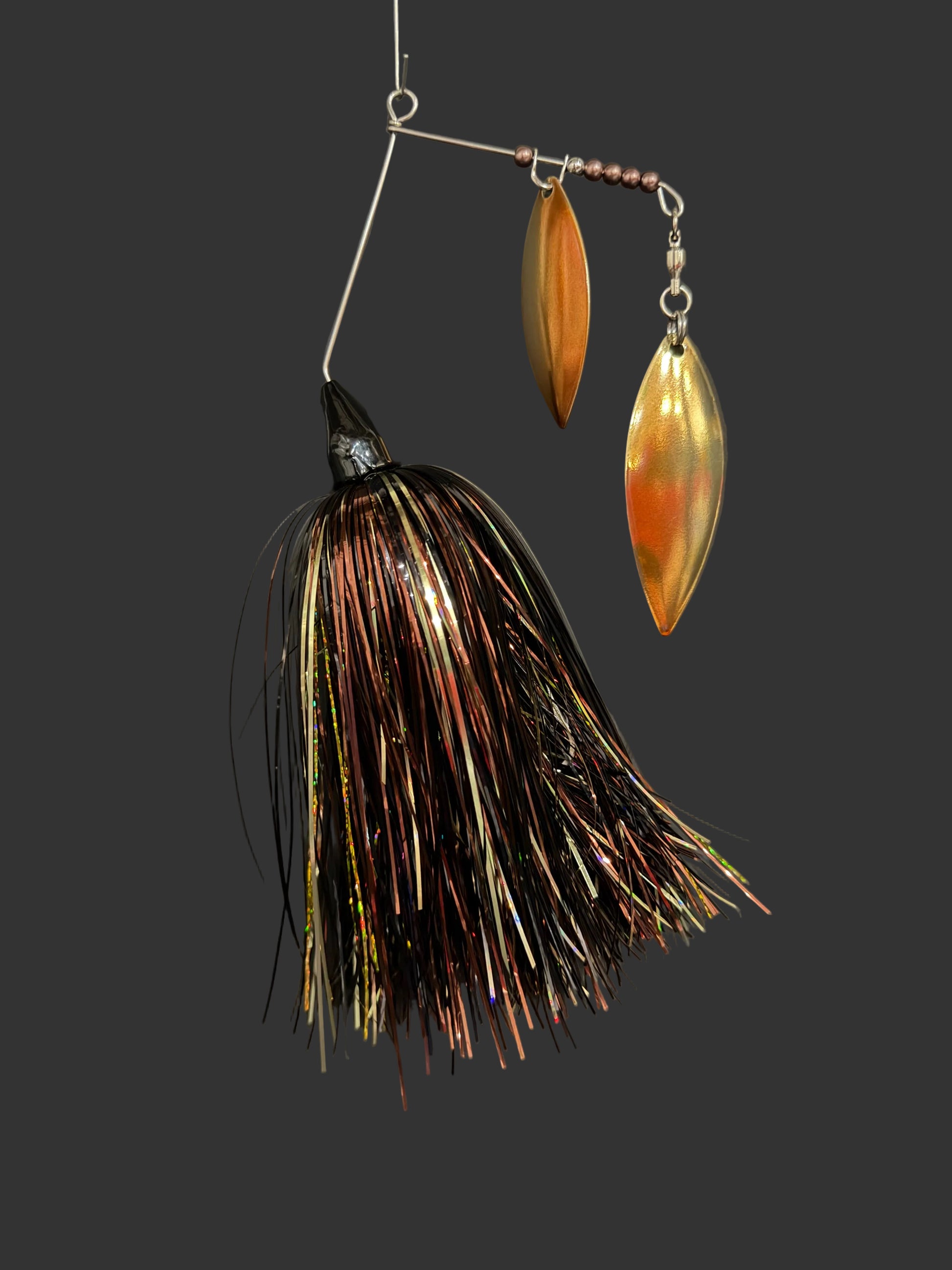 Fishing lure with metallic blades and feathered body on a dark background