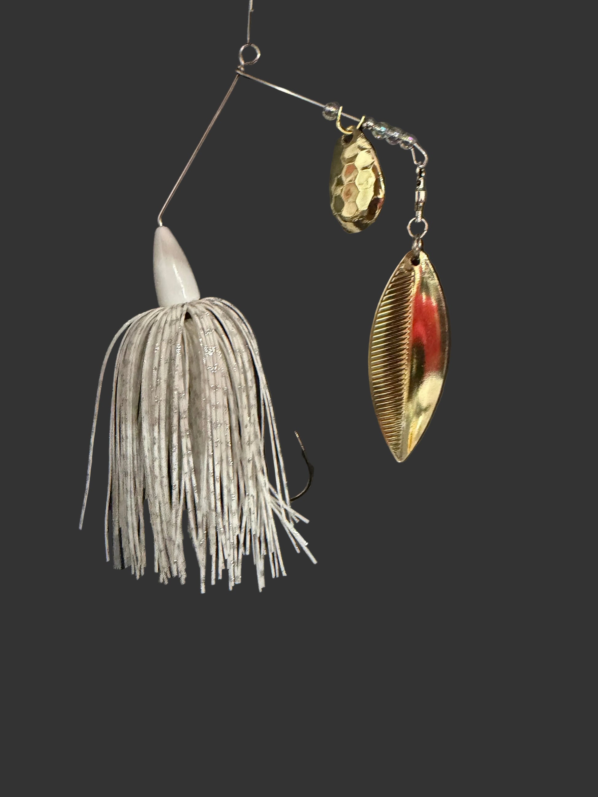 Fishing lure with metallic blade and white skirt on a black background