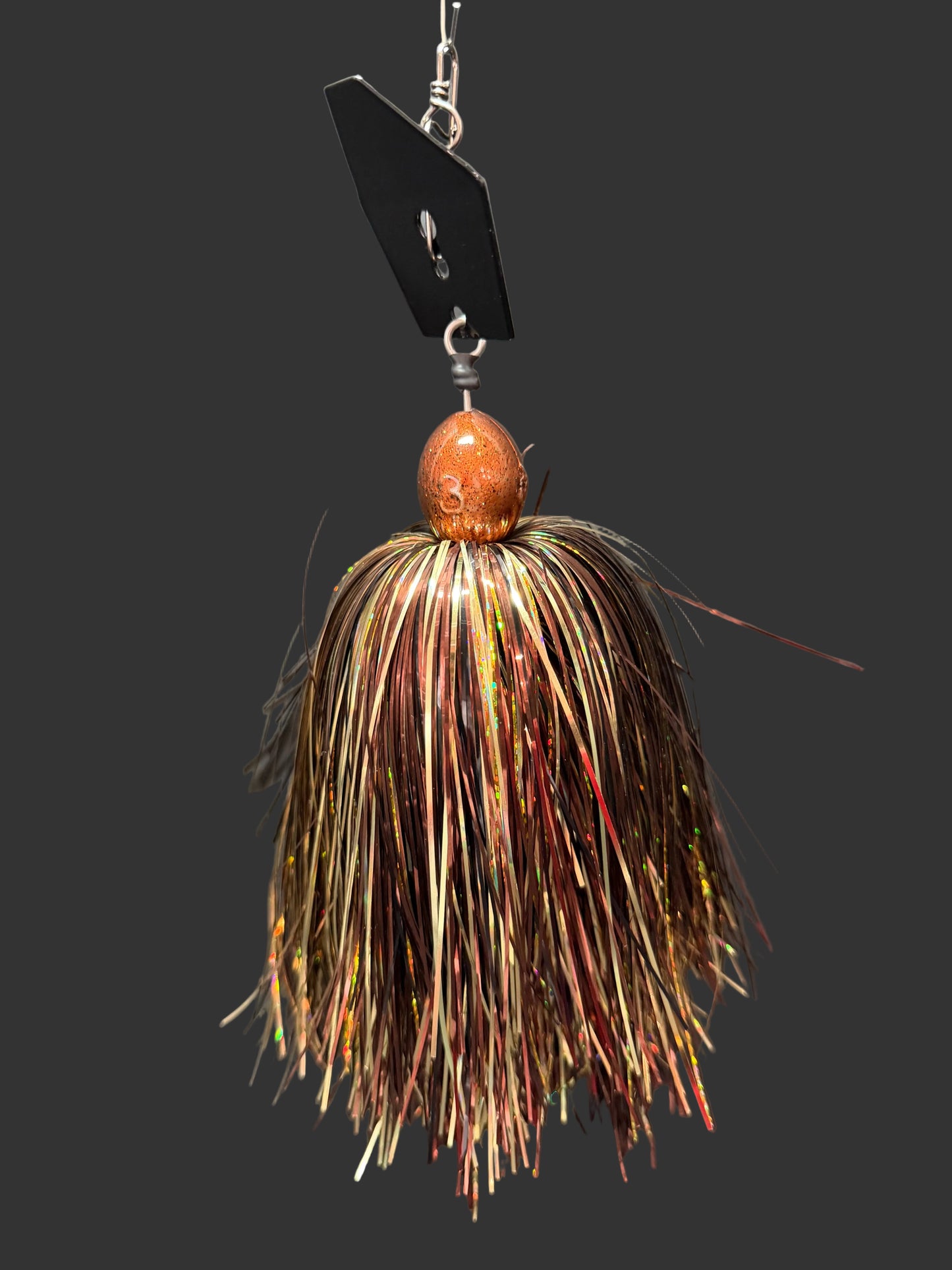 A Muskie chatterbait fishing lure with a black blade and gold and bronze skirt. Made by Lure-cifer in Brantford, Ontario, Canada.
