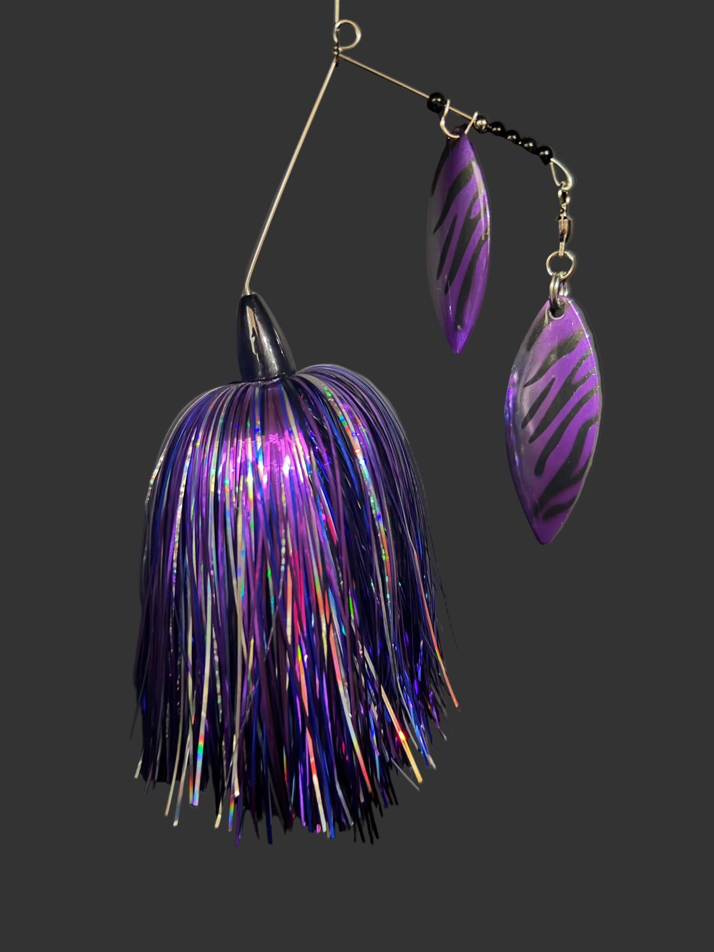 Purple and silver fishing lure on a dark surface