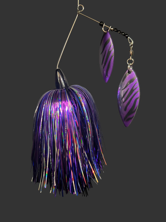 Purple and silver fishing lure on a dark surface