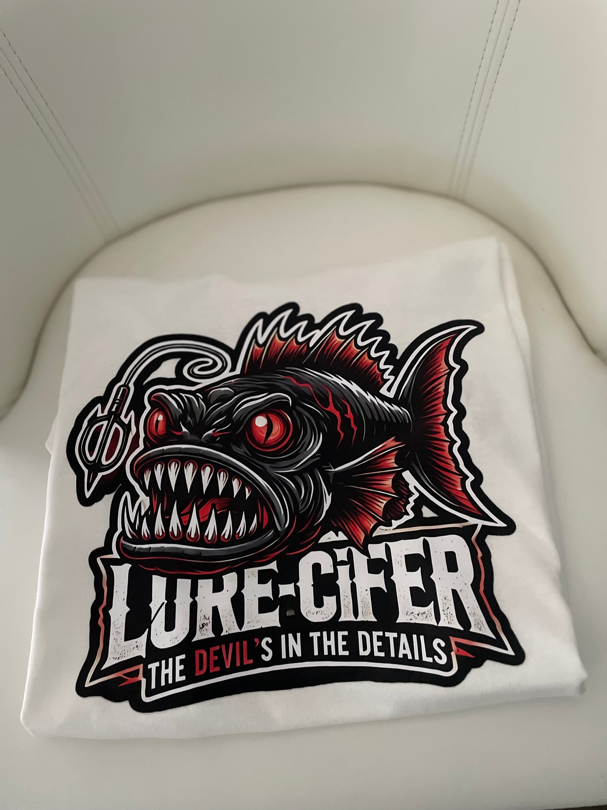 Folded white t-shirt with 'Lure-Cifer' graphic design 